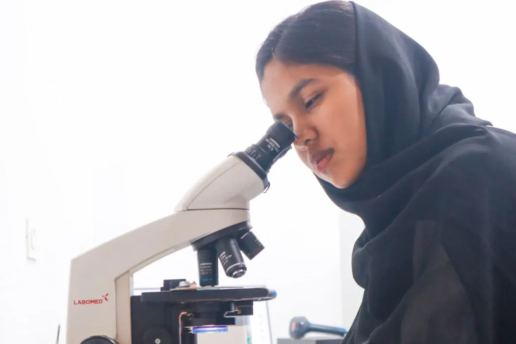 Paramedical student using microscope in clinical lab at Ayurgreen College